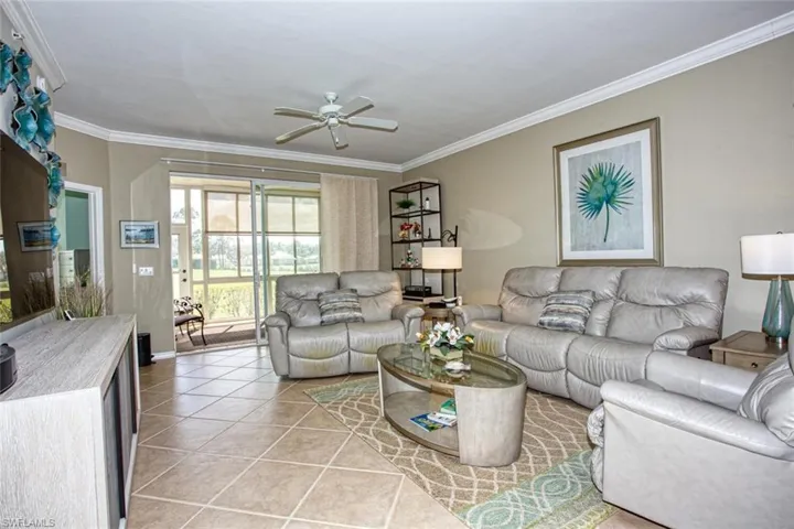 Living room featuring light tile patterned floors, crown molding, and ceiling fan