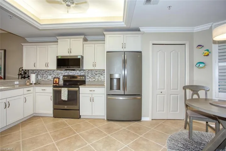 Kitchen with stainless steel appliances, tasteful backsplash, ceiling fan, light tile patterned floors, and crown molding
