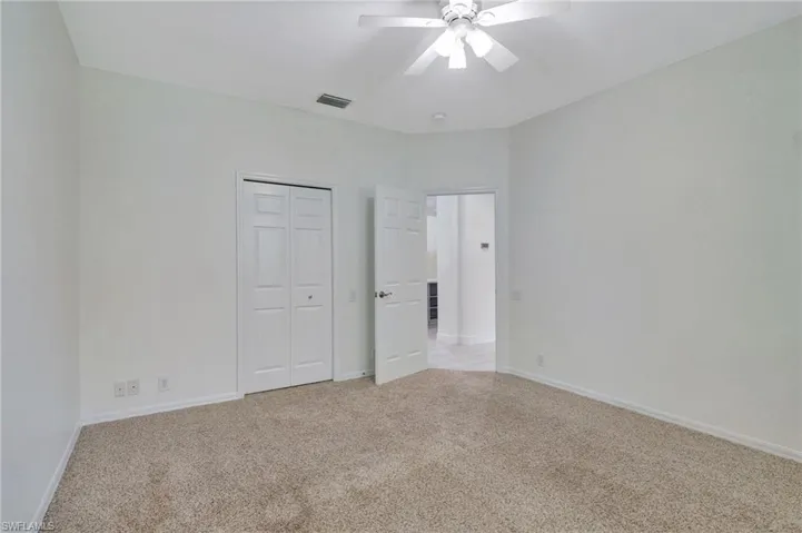 Unfurnished bedroom with ceiling fan, a closet, and light carpet