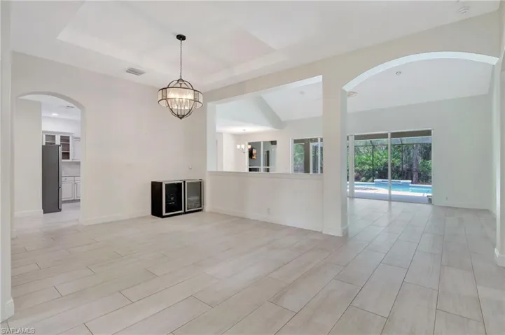 Unfurnished living room featuring a tray ceiling and an inviting chandelier
