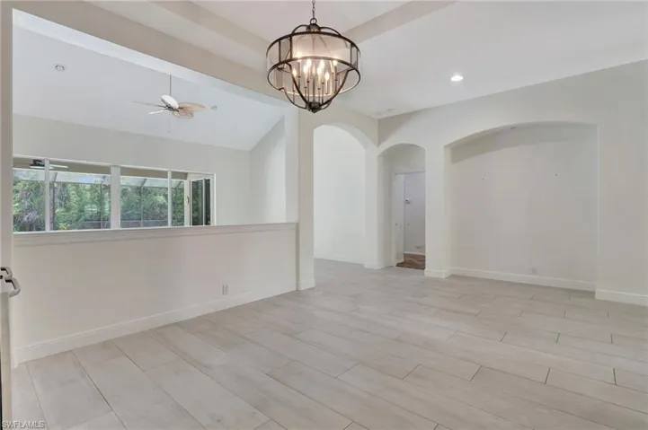 Spare room featuring lofted ceiling and ceiling fan with notable chandelier