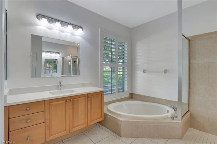 Bathroom with a relaxing tiled bath, tile flooring, and vanity