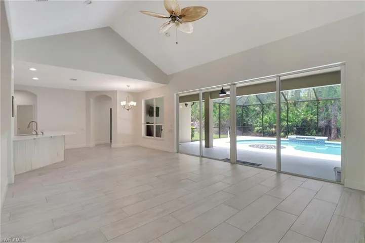 Spare room with high vaulted ceiling, ceiling fan with notable chandelier, a wealth of natural light, and sink