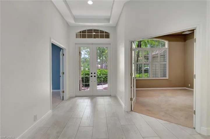 Entryway with light carpet, a towering ceiling, french doors, and a tray ceiling