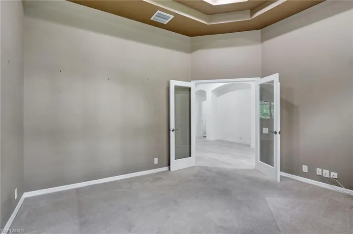 Carpeted spare room with a high ceiling and french doors