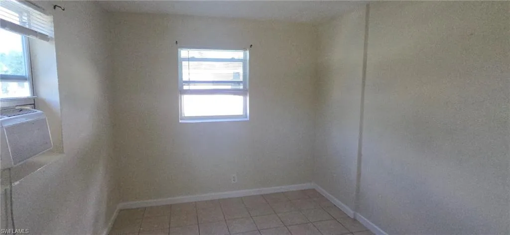 Empty room with light tile patterned flooring and baseboards