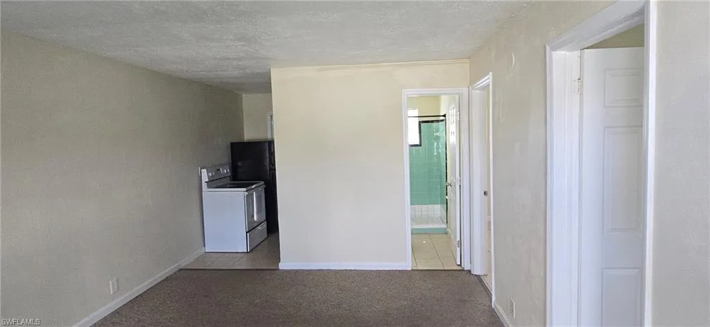 Hallway featuring washer / clothes dryer, carpet, a textured ceiling, and tile patterned flooring