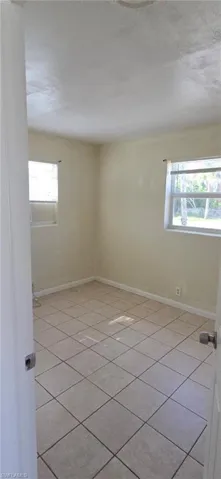 Empty room featuring plenty of natural light and light tile patterned floors
