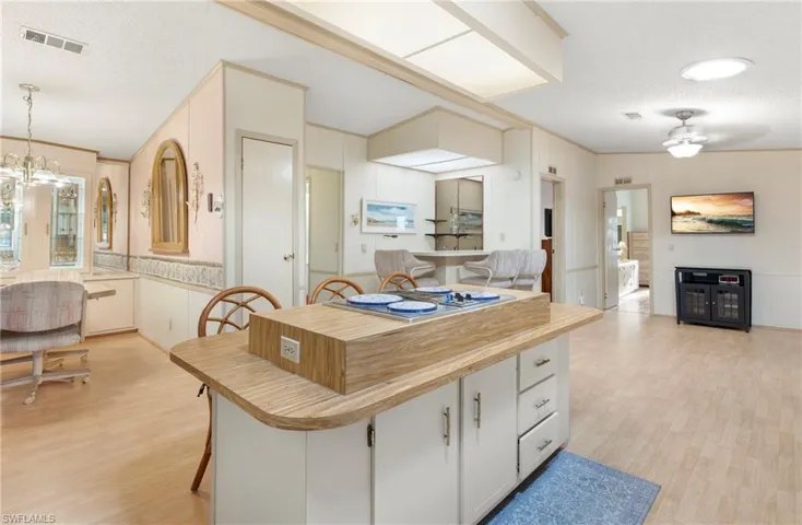 Kitchen with open floor plan, visible vents, light wood-type flooring, and a textured ceiling