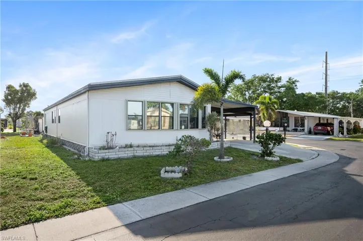 Manufactured / mobile home featuring an attached carport and a front yard