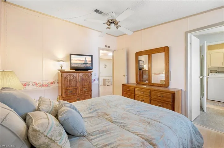 Bedroom featuring a textured ceiling, visible vents, a ceiling fan, and stacked washer / dryer