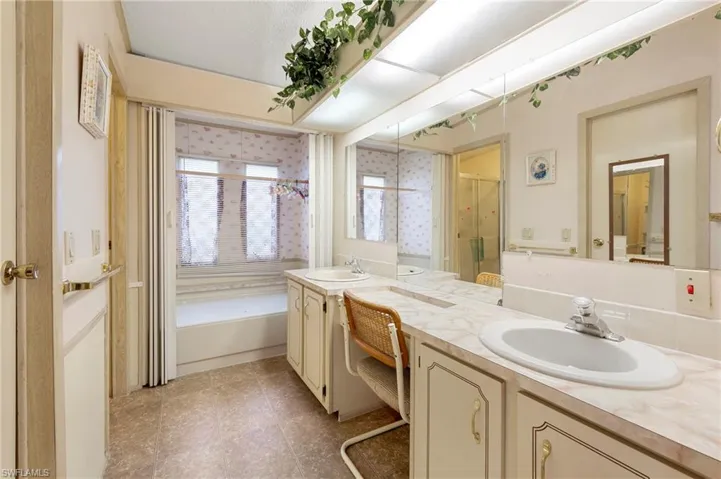 Bathroom with a tub, two vanities, a sink, and walk in shower