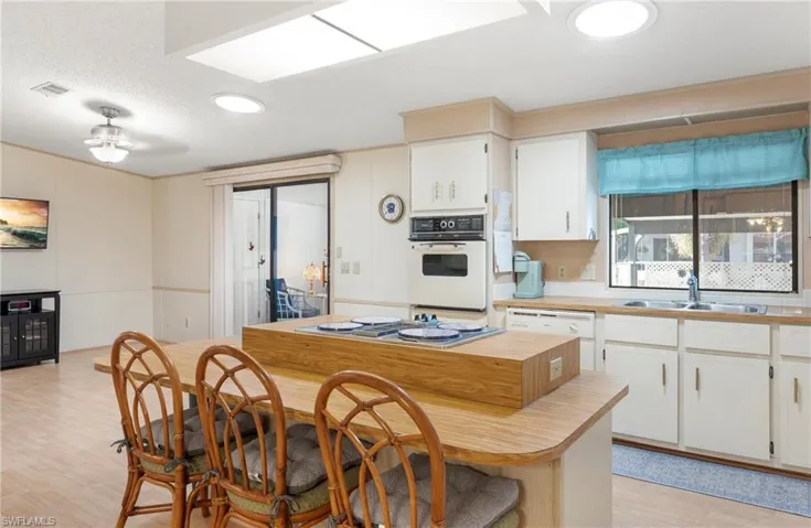 Kitchen featuring visible vents, stainless steel stovetop, white cabinetry, a sink, and light wood-style floors