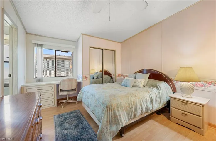 Bedroom with a closet, a ceiling fan, light wood finished floors, a textured ceiling, and ornamental molding