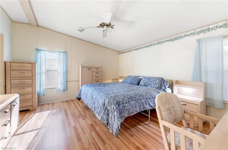 Bedroom featuring lofted ceiling, a ceiling fan, light wood-style floors, and a textured ceiling