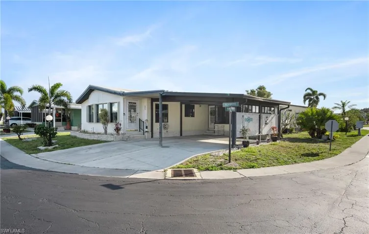 View of front of home with a front yard, a carport, and concrete driveway