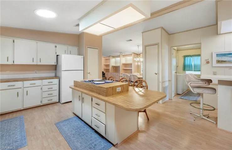 Kitchen featuring freestanding refrigerator, light wood-style flooring, white cabinetry, and a breakfast bar