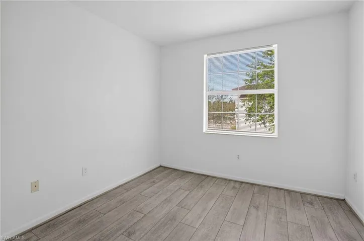 Room with light gray wood-finish flooring, white walls, and white baseboards
