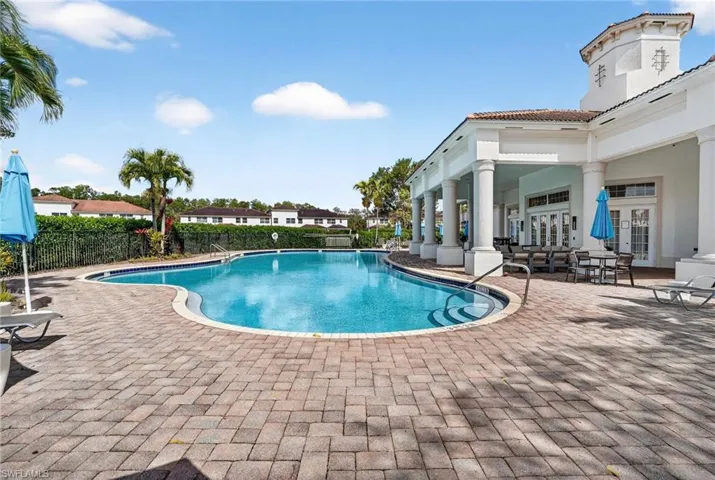 Curved swimming pool with paver decking and a covered outdoor lounge area