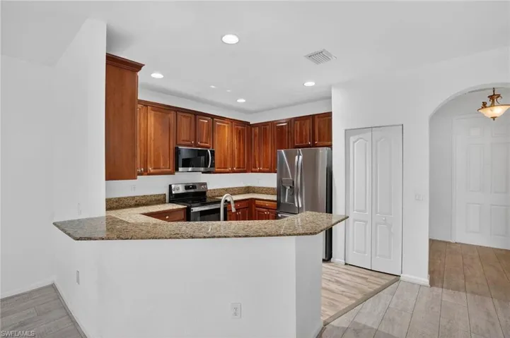 Kitchen featuring wood cabinetry, granite countertops, stainless steel appliances, and recessed lighting