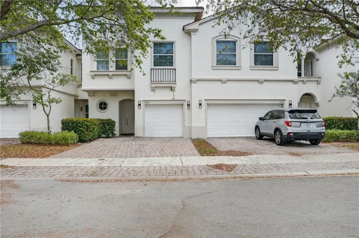 Stucco exterior featuring dual garage entrances and a paver driveway