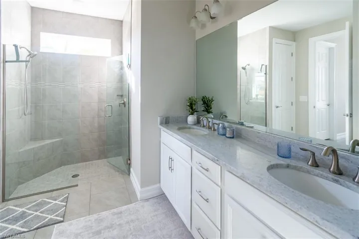 Bathroom with double vanity, a stall shower, and light tile patterned floors
