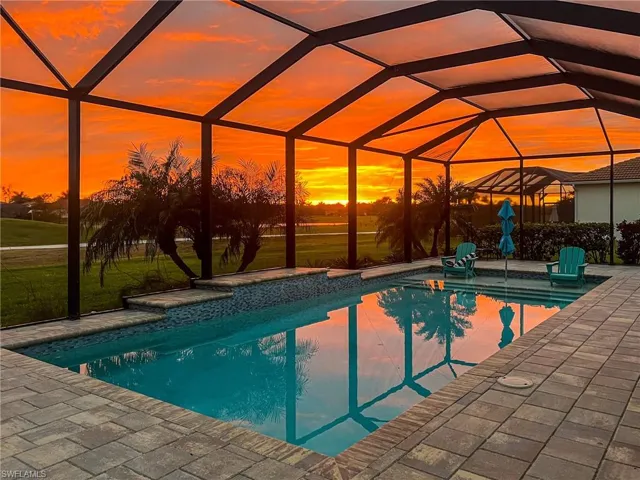 Swimming pool featuring glass enclosure, a sunroom, a patio, and a yard