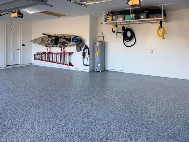 Garage featuring electric water heater and a garage door opener