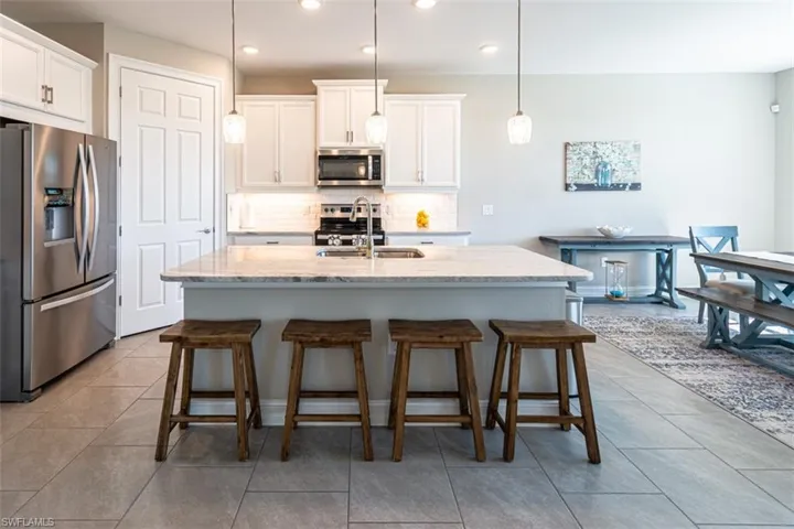 Kitchen featuring stainless steel appliances, a breakfast bar area, a center island with sink, and white cabinets