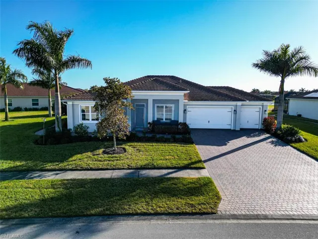 View of front facade featuring a front lawn, a garage, decorative driveway, stucco siding, and a tiled roof