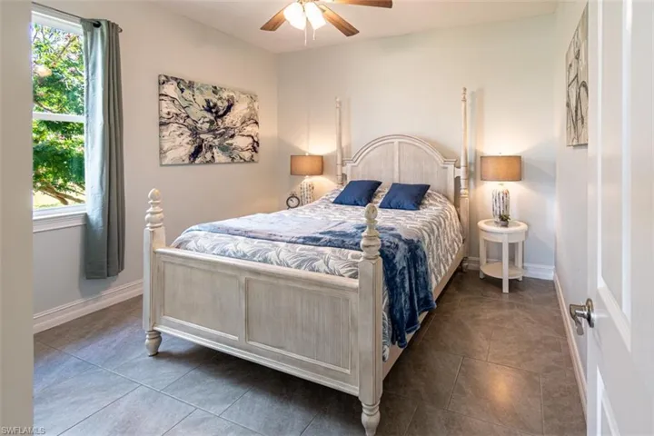 Tiled bedroom featuring ceiling fan and baseboards