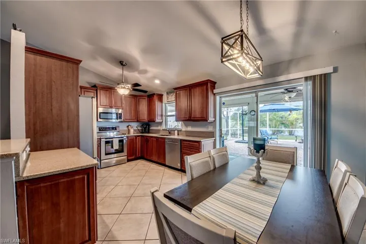 Kitchen with light tile patterned flooring, appliances with stainless steel finishes, sink, hanging light fixtures, and ceiling fan