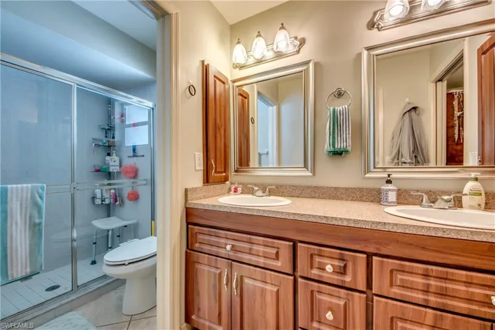 Bathroom with tile patterned flooring, vanity, an enclosed shower, and toilet