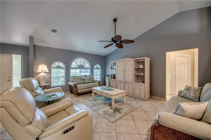 Tiled living room featuring ceiling fan and high vaulted ceiling