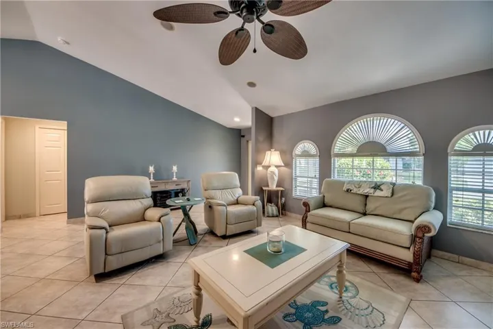 Tiled living room with ceiling fan and vaulted ceiling