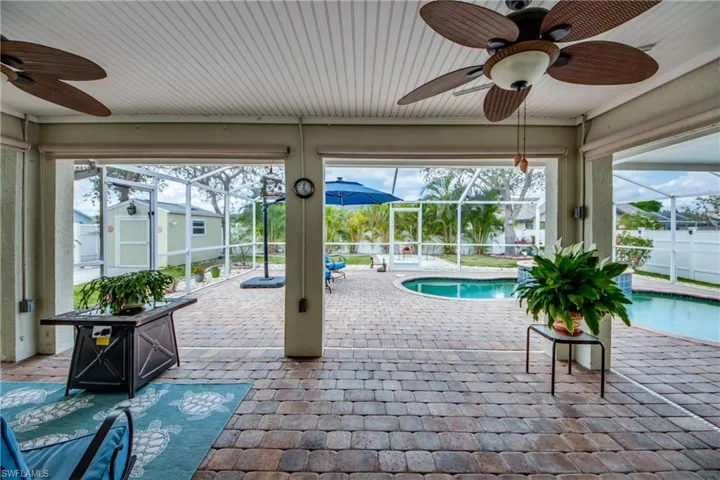 View of pool with ceiling fan, a storage unit, glass enclosure, and a patio area