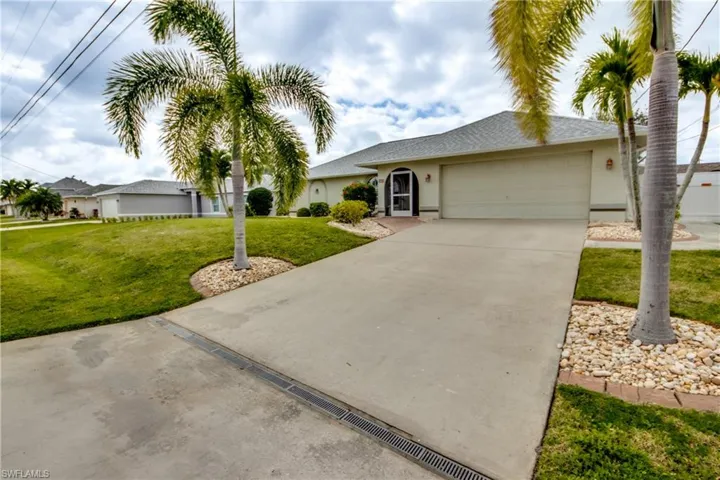 Ranch-style house featuring a garage and a front lawn