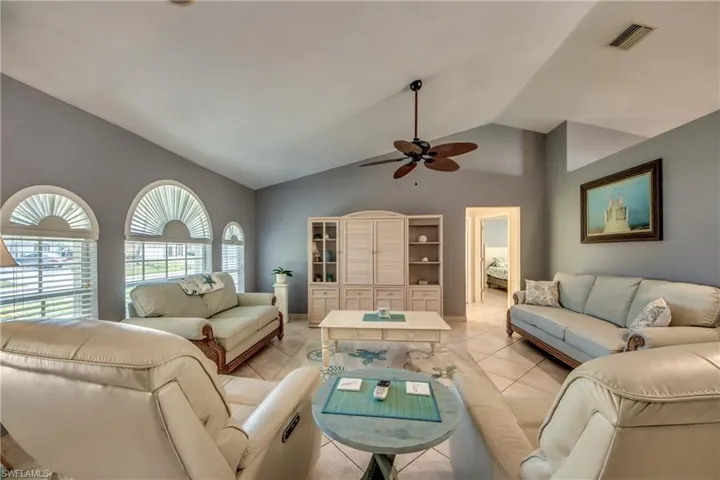Living room with light tile patterned flooring, vaulted ceiling, and ceiling fan