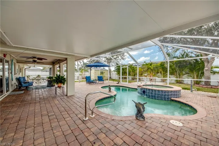 View of swimming pool with an in ground hot tub, glass enclosure, and a patio area