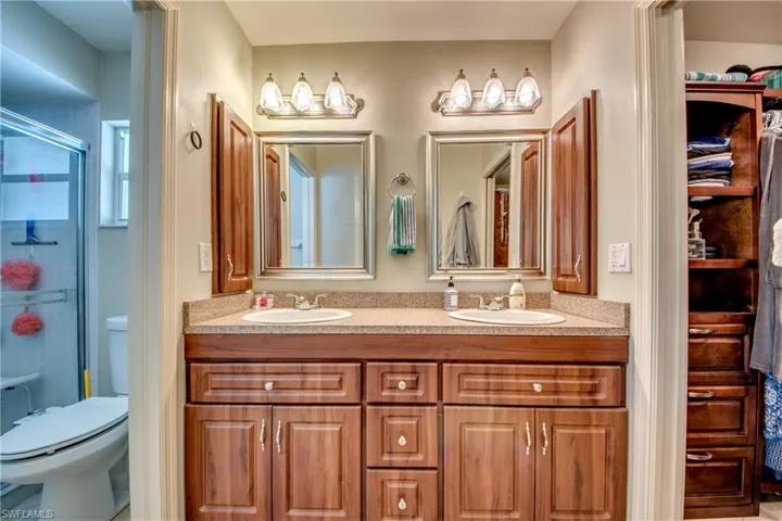 Bathroom with a shower with door, vanity, and toilet