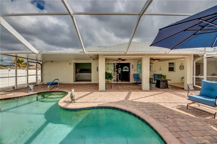 View of swimming pool with a patio area, ceiling fan, and glass enclosure