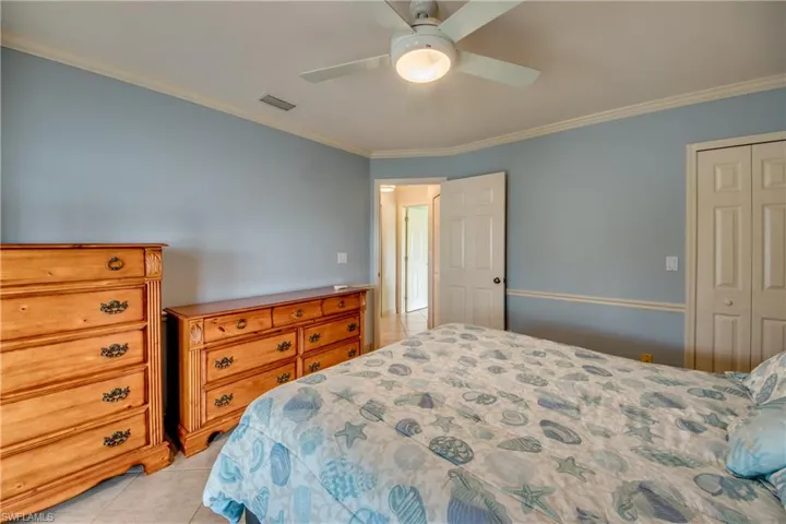 Bedroom featuring light tile patterned floors, ornamental molding, a closet, and ceiling fan