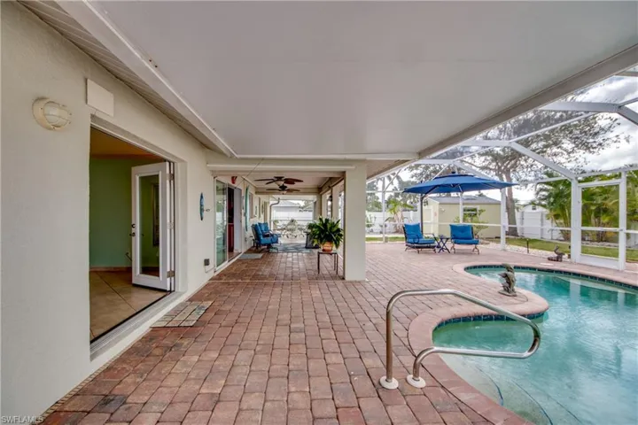 View of pool featuring a patio area, ceiling fan, and glass enclosure
