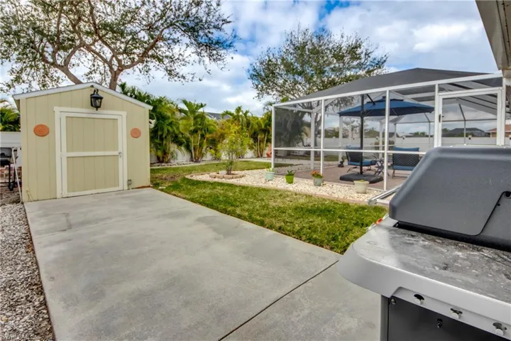 View of yard with a shed, glass enclosure, and a patio area