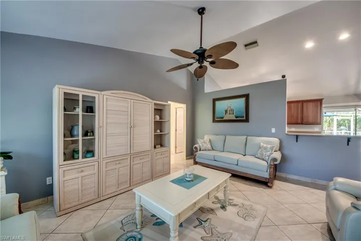 Tiled living room with vaulted ceiling and ceiling fan