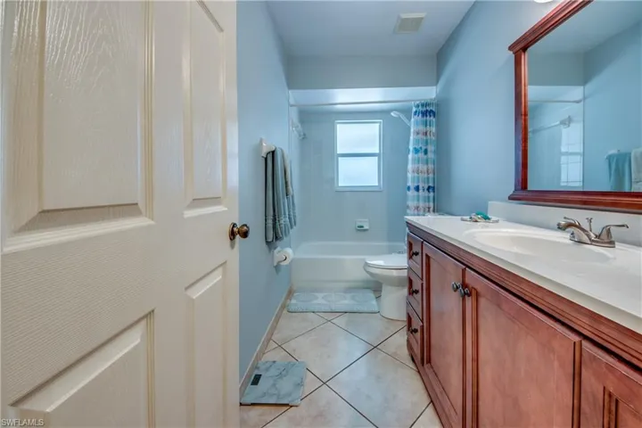 Full bathroom featuring shower / tub combo with curtain, tile patterned floors, toilet, and vanity