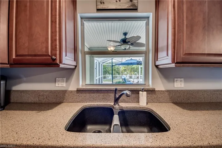 Kitchen with sink, light stone countertops, and ceiling fan