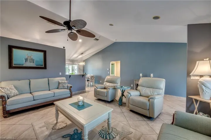 Tiled living room featuring ceiling fan and vaulted ceiling