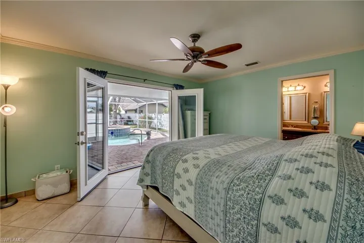Bedroom with ensuite bathroom, light tile patterned floors, access to exterior, ceiling fan, and crown molding