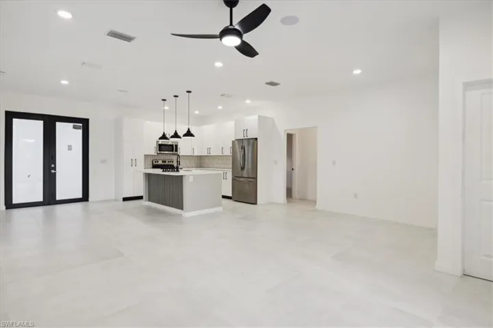 Kitchen with pendant lighting, appliances with stainless steel finishes, an island with sink, ceiling fan, and white cabinets